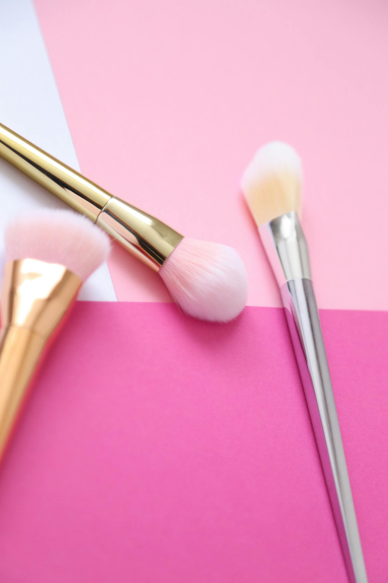 Close-up of stylish makeup brushes on a minimalist pink backdrop, ideal for beauty themes.